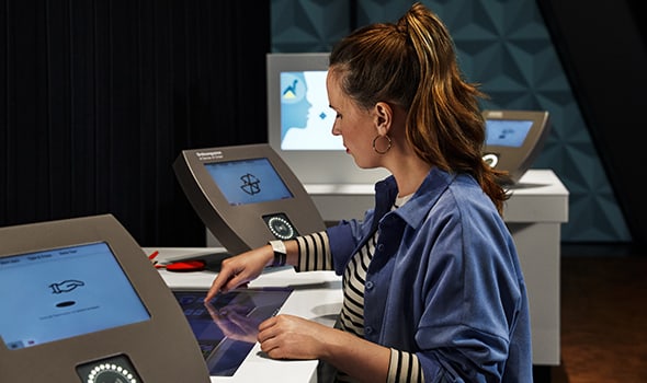 Frau sitzt am Touchscreen an einer Talentstation