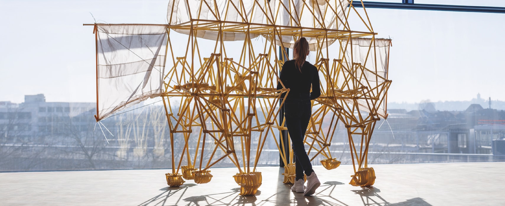 Jugendliches Mädchen schiebt das Strandbeest vor einer großen Fensterscheibe