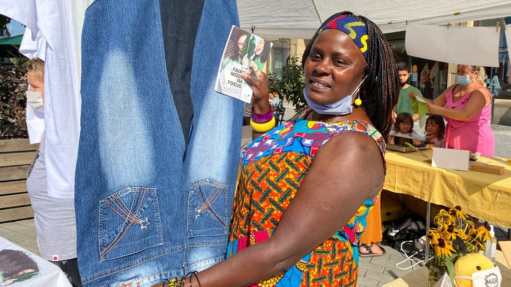 Frau zeigt Jeanskleid am Marktstand