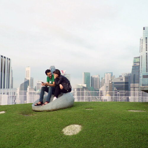Mann und Frau sitzen auf einem Stein auf einer grüner Wiese