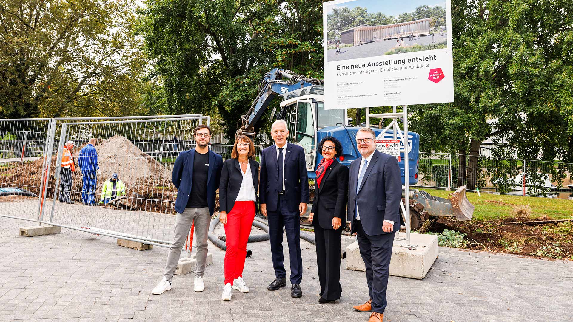 Moritz Gräter (CEO Ipai), Silke Lohmiller (Geschäftsführerin Dieter Schwarz Stiftung), Harry Mergel (Oberbürgermeister Stadt Heilbronn), Prof. Dr. Bärbel Renner (Geschäftsführerin experimenta), Andreas Ringle (Bürgermeister Stadt Heilbronn) vor dem Bauschild des KI Pavillions.
