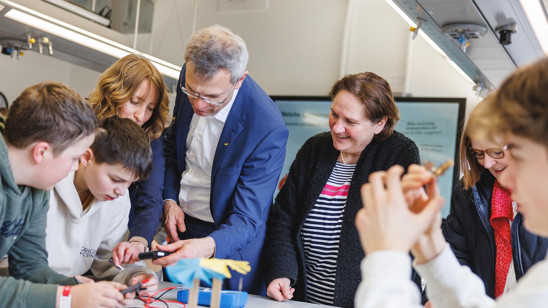 Schülerinnen und Schüler und Lehrpersonen experimentieren zusammen an einem Stromkreislauf.