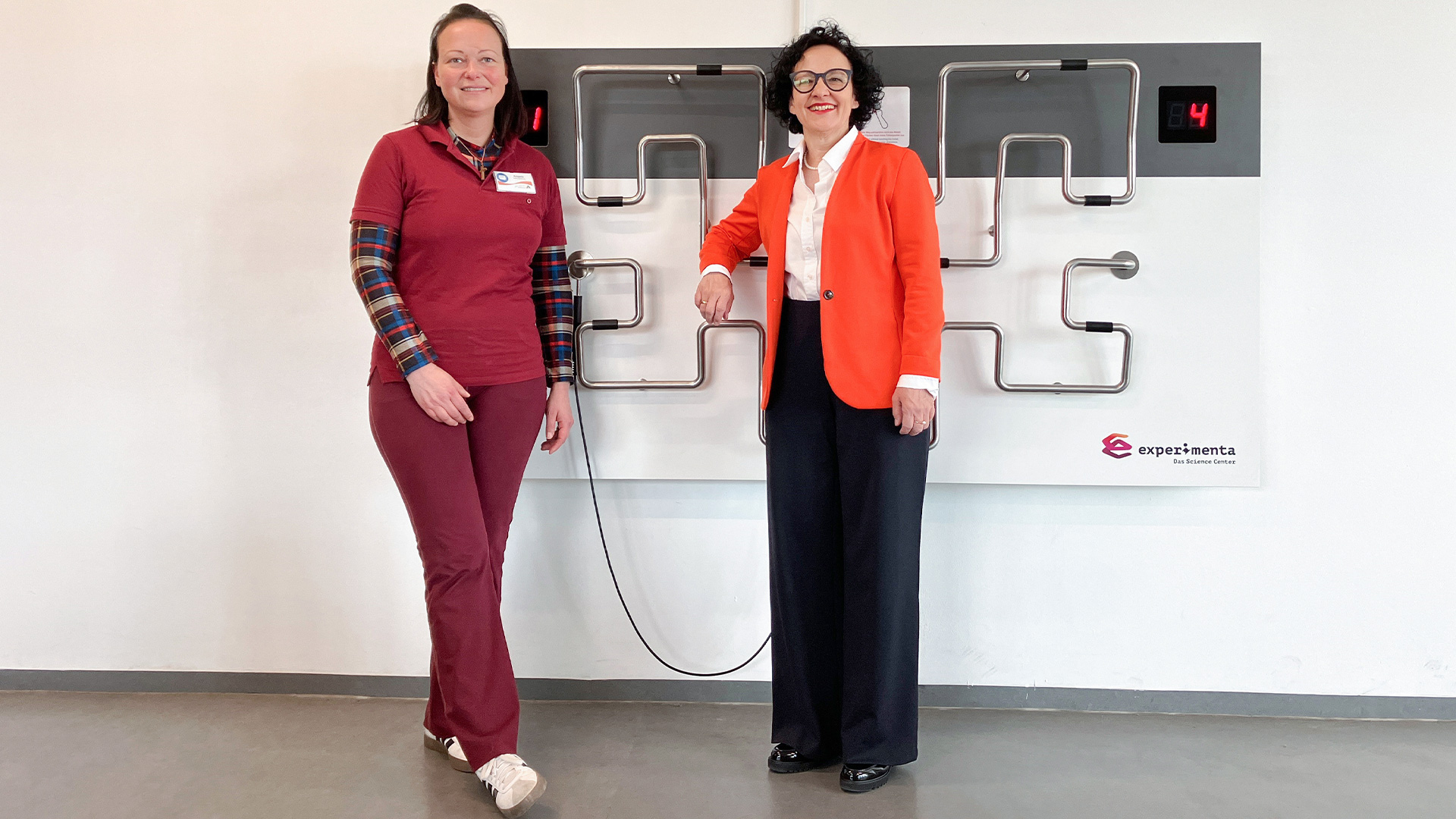 Angela Kachel und Prof. Dr. Bärbel Renner stehen gemeinsam vor dem interaktiven Exponat „Kurvengeschick“ der experimenta in der Jugendherberge Heilbronn.