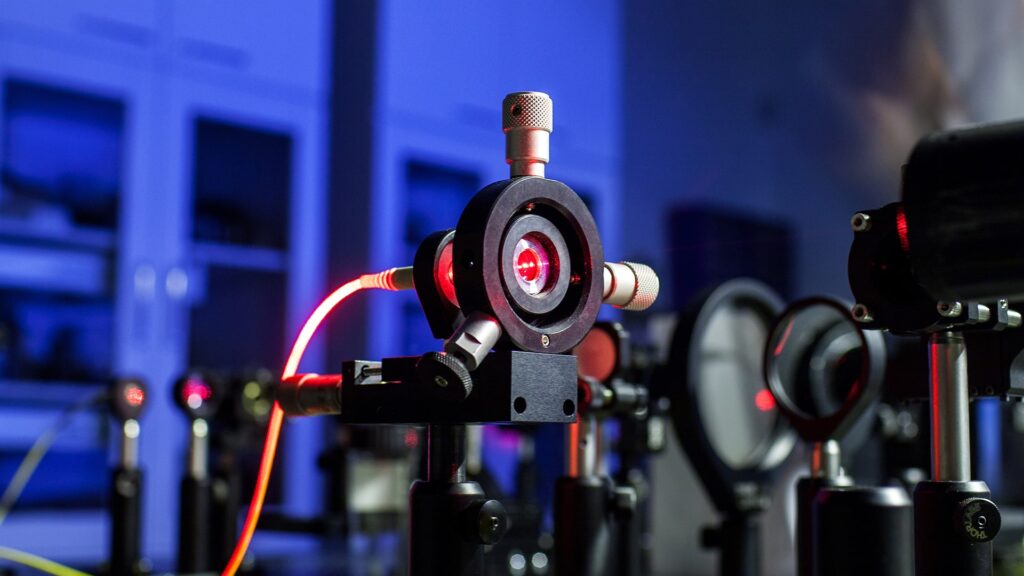 Optischer Aufbau mit rotem Laserstrahl im Labor, symbolisch für Quantenexperimente und Lichtinterferenz.