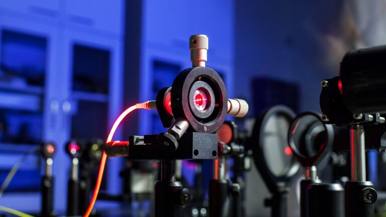 Optischer Aufbau mit rotem Laserstrahl im Labor, symbolisch für Quantenexperimente und Lichtinterferenz.