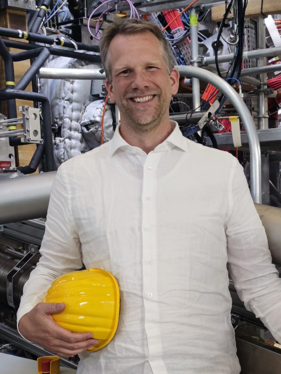 Physiker Dr. Birger Buttenschön mit Schutzhelm vor einer Anlage zur Erforschung der Kernfusion