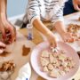 Familie beim gemeinsamen Plätzchen backen und Verzieren am Tisch