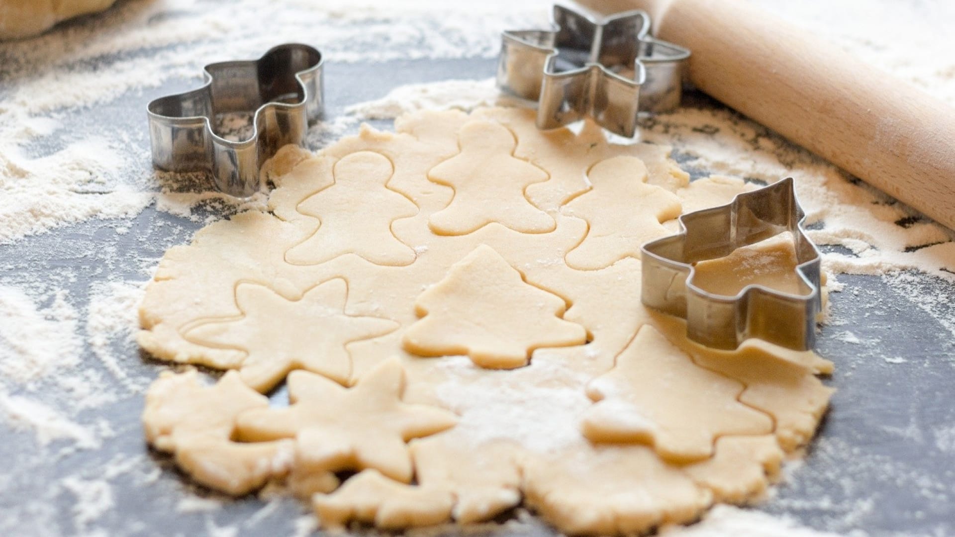 Ausgestochener Plätzchenteig mit Sternen, Bäumen und Lebkuchenmännern beim Plätzchen backen